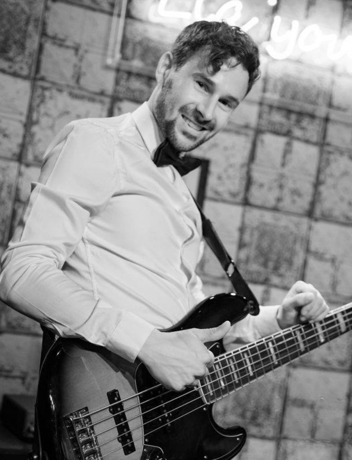 Black-and-white portrait of a musician holding an electric bass guitar