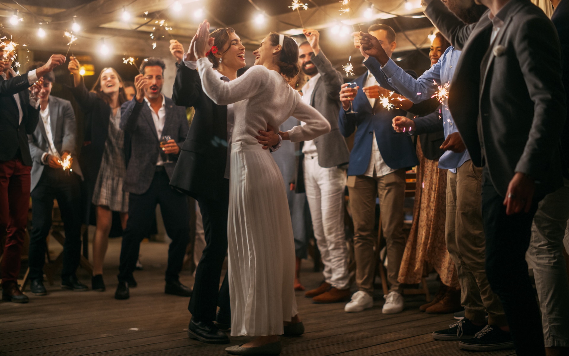 Couple sharing an emotional wedding dance surrounded by guests and sparklers