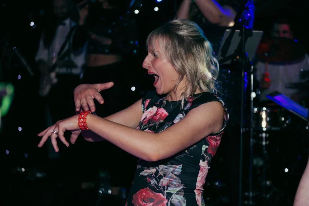 A wedding guest dancing in front of the band’s microphones and drum kit