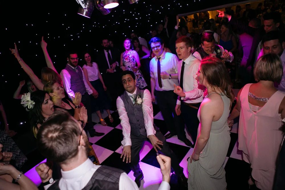 The groom dancing in the middle of a circle of wedding guests beside the live band