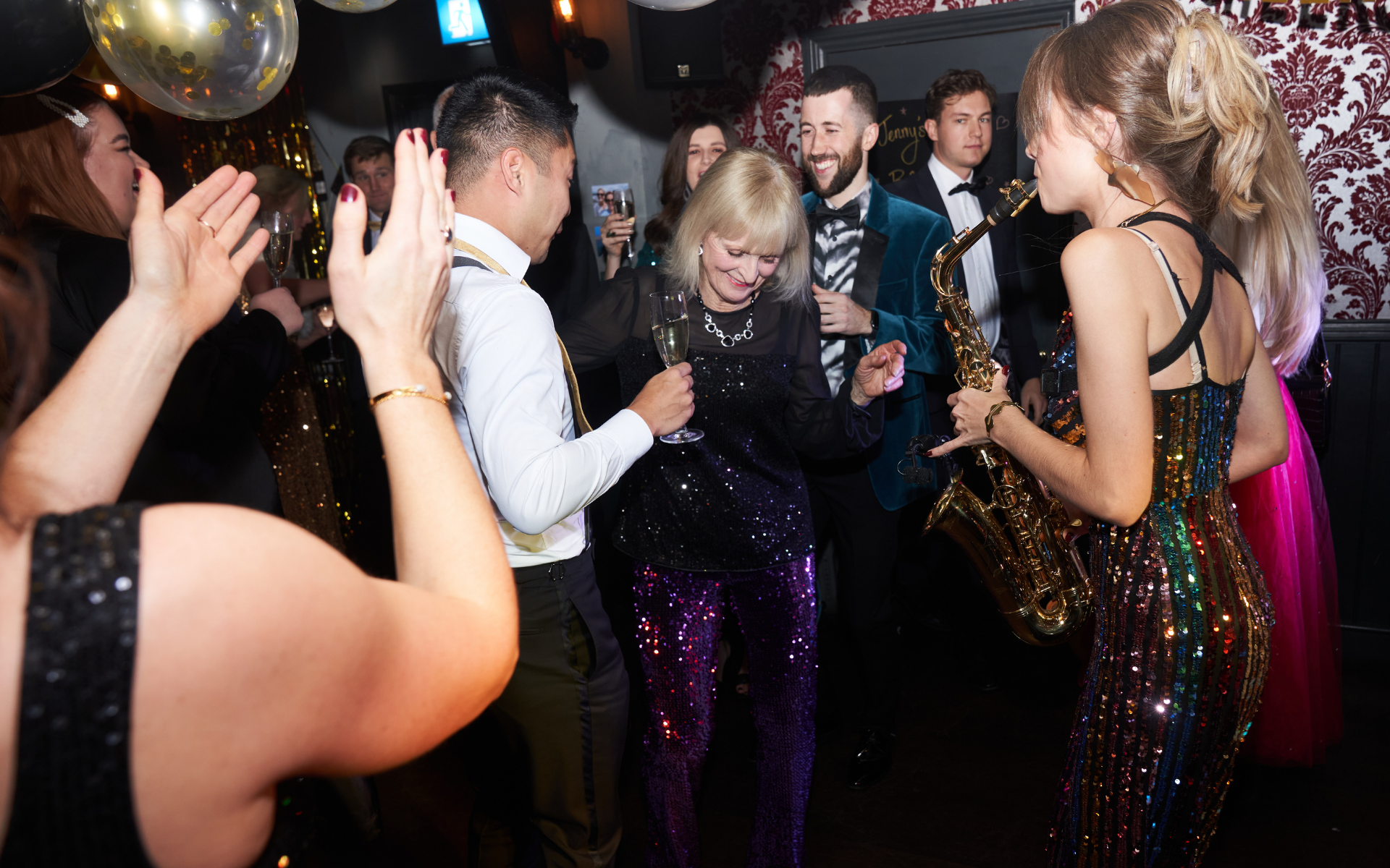 Saxophonist performing among guests on a packed dance floor